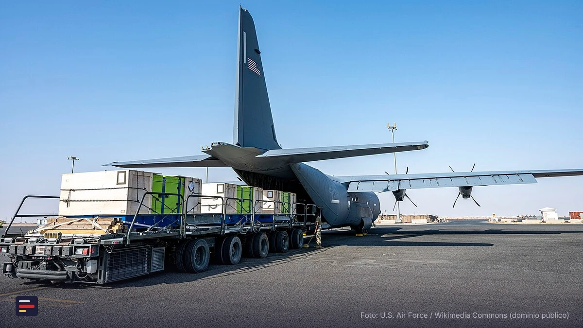 Avión de carga C-130 cargando palets de ayuda humanitaria en una pista de aterrizaje